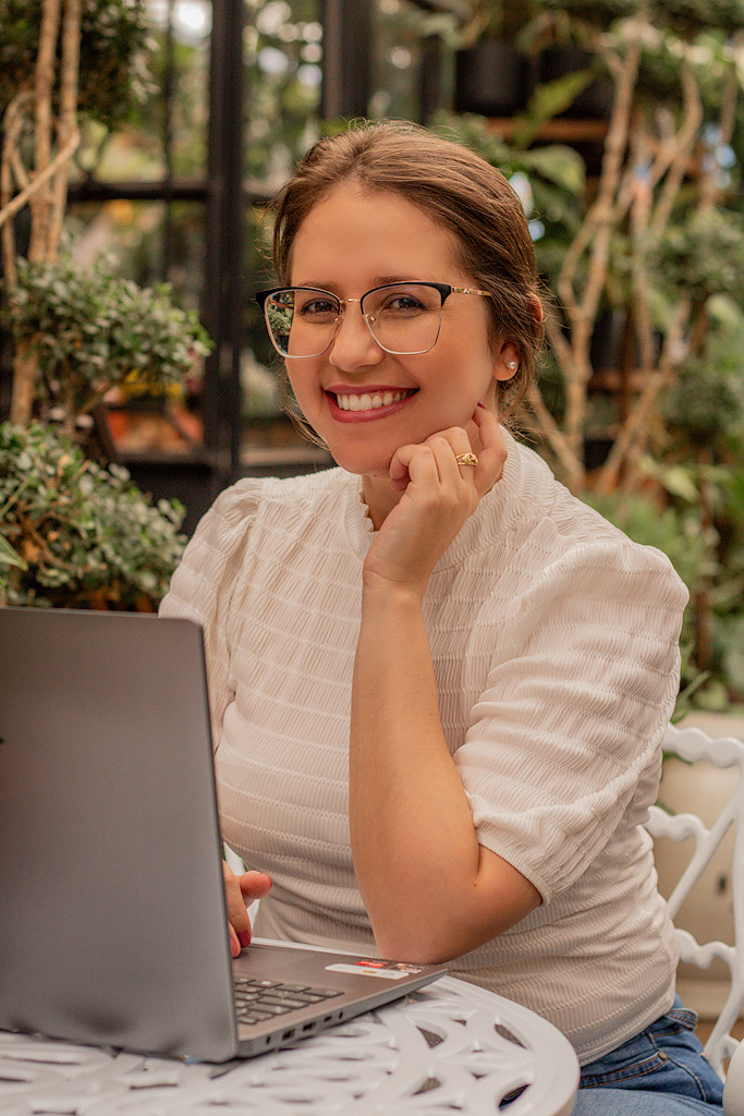 Fernanda Goulart Ferreira sorrindo, sentada com um notebook